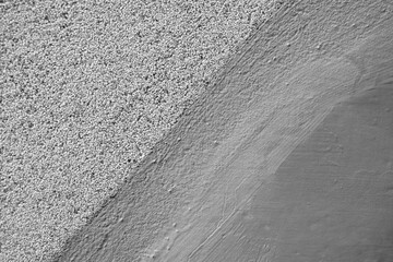 Surface of grey concrete wall with different structure - grainy and smooth, painted. Clear diagonal border, brush marks. Selective focus. Copy space for text.