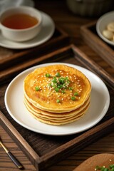 a close up of a plate of pancakes with a cup of tea