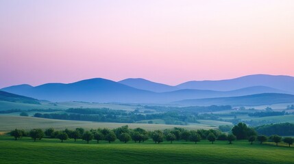 Obraz premium Calm rural landscape with apple trees and distant mountains under pastel skies