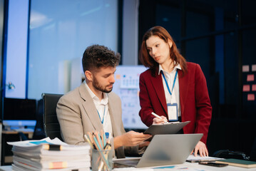Two office colleagues discuss ideas for a startup project in a modern workspace, using laptops and smartphones