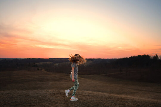 Profile young girl long hair blowing twirling outdoors sunset