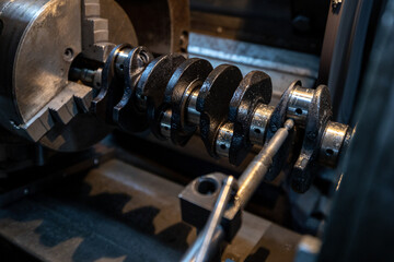 Fototapeta premium A crankshaft is securely mounted in a grinding machine within a workshop, undergoing the process of crankshaft grinding