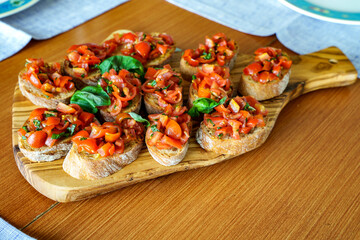 Bruschetta served on a wooden board. Freshly toasted bread with chopped tomatoes, garlic, basil,...