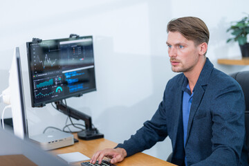 Fototapeta premium Man working on computer analyzing data in modern office environment during daytime