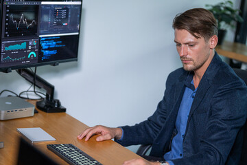 Business professional analyzing market data on computer with multiple monitors in modern office space