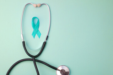 Teal Awareness Ribbon Surrounded By Stethoscope On Turquoise Background.