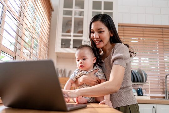 Asian single mother lovingly cares for and raises her baby boy in house.