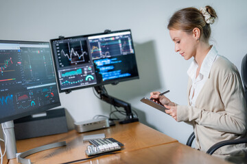 Professional trader analyzes market data while documenting strategies in a modern office