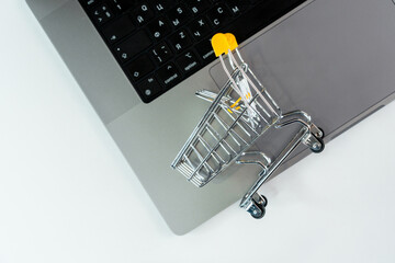 Bank or credit cards and a supermarket cart on a laptop keyboard, an online shopping concept.