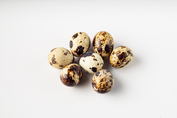 Fototapeta premium Seven quail eggs on a white surface.
