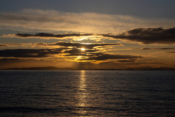 Golden sunset illuminates the ocean horizon with serene beauty and gentle waves reflecting brilliant colors