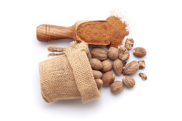 A scoop of organic Nutmeg (Myristica fragrans) powder, along with nutmeg seeds spilled out from a jute bag. Isolated on a white background.