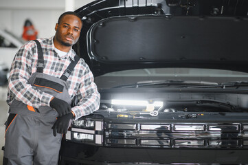 An African-American mechanic confidently posing with tools in hand in his workshop