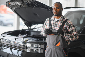 Skilled mechanic technician working at service station, repairing car