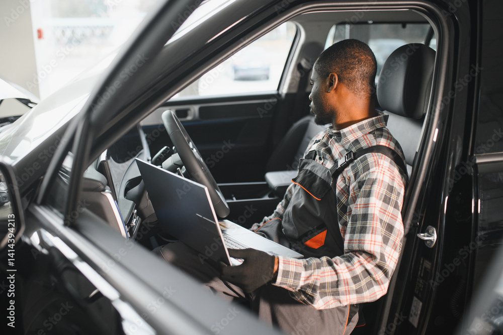 Aufkleber Black auto mechanic running diagnostic on laptop while analyzing engine problems in a workshop