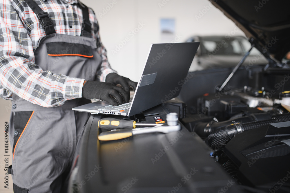 Poster Black auto mechanic running diagnostic on laptop while analyzing engine problems in a workshop