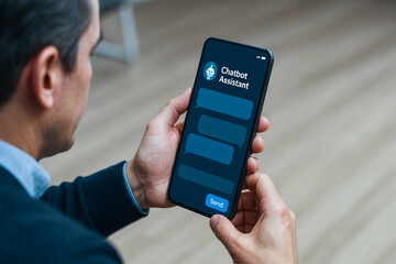 Chatbot Assistant Interface on Smartphone. A man holding a phone with a chatbot app showing empty conversation bubbles, representing AI virtual assistant.