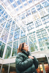 Fototapeta premium Outdoor portrait of happy woman looking at glass building