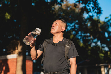 Middle aged man recovering after ruck walk, feeling quenched while rehydrating under the morning...