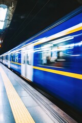 Fototapeta premium Captivating motion blur of a vibrant blue train speeding through a modern subway station platform offering a dynamic urban transportation scene