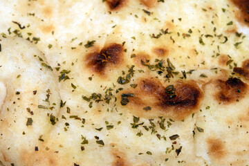 Close up of the surface of a fresh flatbread bread with herbs