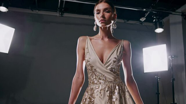 Female model in silver sequin gown with deep V-neckline posing in professional studio, glamorous evening wear fashion portrait with clean backdrop