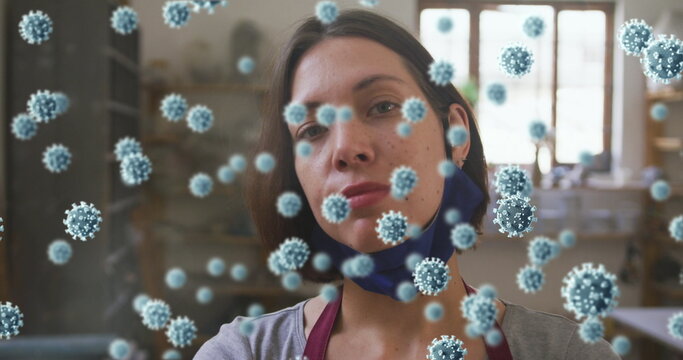 Composite image of covid-19 cells floating against female caucasian potter smiling