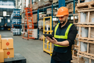 Warehouse worker managing logistics and goods transportation to the market. Man walking  and using tablet to control distribution.