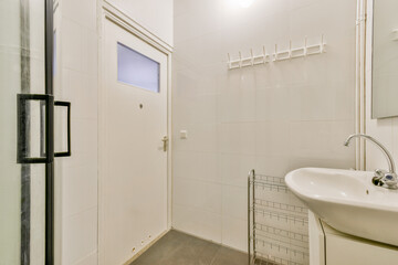 A spacious and bright bathroom featuring a minimalist design with white tiles, a modern sink, and a stylish shower area.