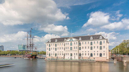 Fototapeta premium Hyperlapse of the National Maritime Museum with the sailboat replica Amsterdam docked nearby. Amsterdam, Netherlands