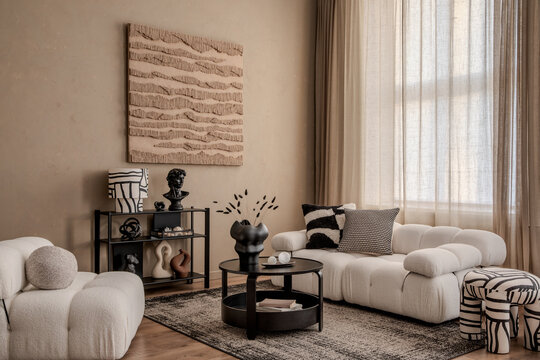 Modern living room with sculptural wall art, tufted sofa, black decor accents and warm beige curtains...