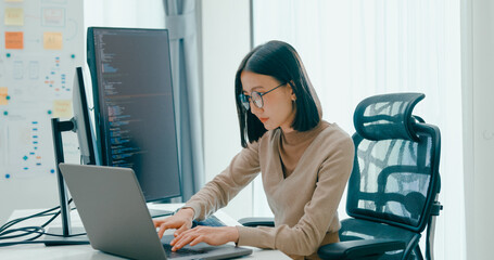 Young adult Asia female freelance eyeglasses typing write prompt AI bot IT app smart program nomad, video game, terminal with coding, user interface, designer, big data center on desktop computer.