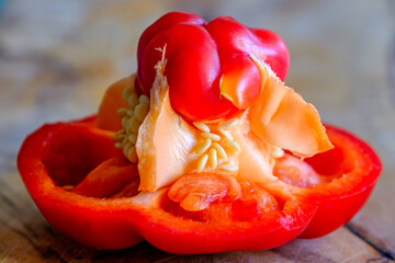 Bright red bell pepper cut open revealing seeds and inner cavity on wooden surface in kitchen setting