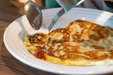 A traditional Malaysian flatbread, roti canai, served with curry sauce on a plate, showcasing its...