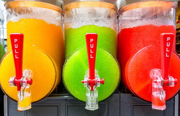 Colorful beverage dispensers with bright options serving refreshing drinks in a lively setting at a summer festival