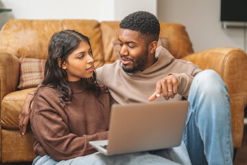 Couple enjoys cozy time together while browsing on a laptop in their warm living room during a...