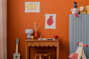 Bright art nook with handmade kids’ drawings, a mushroom lamp, and art tools, styled against a...