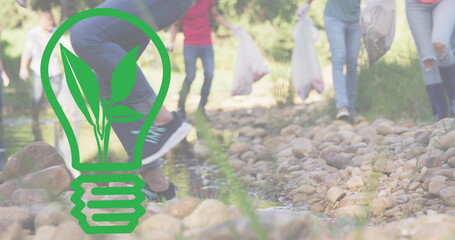 Image of light bulb icon over diverse people cleaning in forest