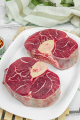 Raw ossobuco beef meat with spices and fresh herbs. Veal shank steak, traditional Italian ingredient
