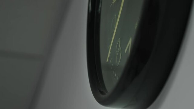 Close-up macro shot time-lapse of black clock face in daytime of office dark grey