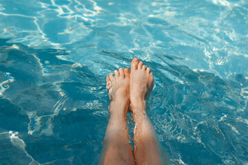 A girl's feet in a blue pool. Epilation of legs, varicose veins. Rest, relaxation on the beach, at...