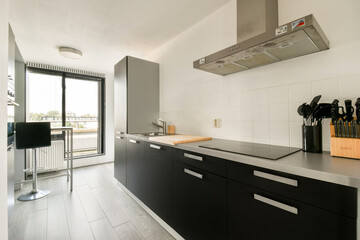 A sleek and contemporary kitchen featuring minimalistic furniture, modern appliances, and ample natural light from large windows.