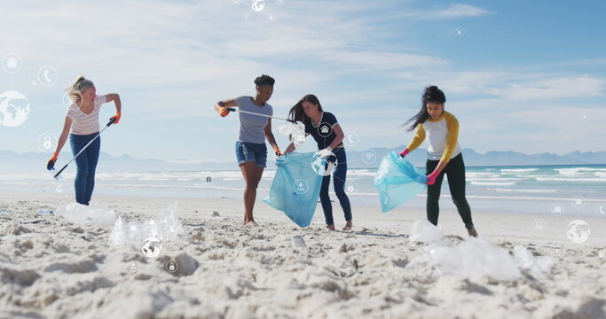 Image of globe icons over diverse female and male volunteers picking up rubbish on beach - Powered by Adobe