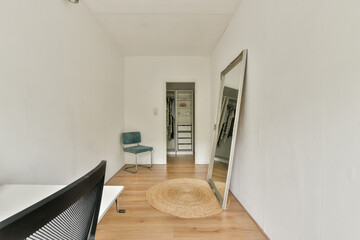 A simple yet elegant room showcasing a large mirror, a chair, and wooden flooring, highlighting...
