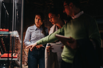 A group of people observing exhibits in a museum, engaging in a discussion while pointing and...