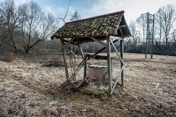 An abandoned concrete well in a rural area in early spring.
