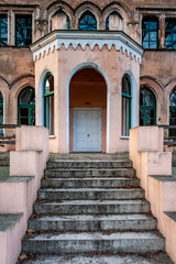 Large, elegant Odziena Manor, a castle built in the neo-Gothic style. Stairs lead to the door entryway of the mansion. Rear facade. Latvia.