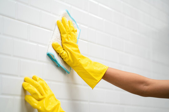 female house cleaner working cleaning wall wearing gloves using rag. housekeeper service doing chores disinfect and wipe kitchen surface with towel. professional housework staff woman cleaning wall