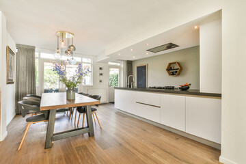 A contemporary kitchen featuring sleek cabinetry, stylish lighting, and a cozy dining area adorned with flowers, enhancing the room's inviting atmosphere.