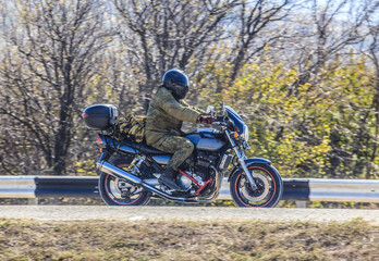 Obraz premium motorcyclist on a motorcycle moves along a country road